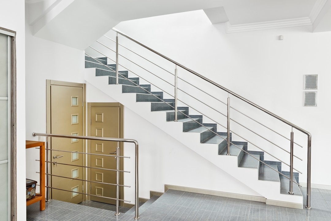 Un escalier en carrelage, la rampe en métal dans un bureau.